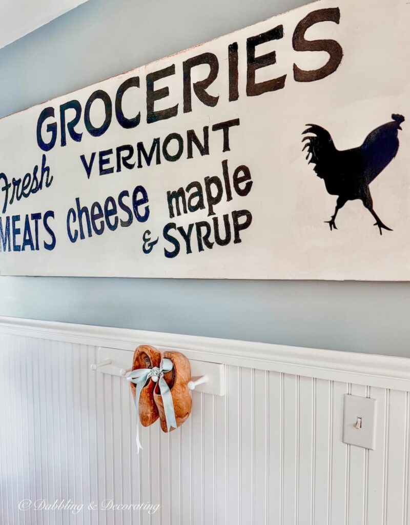 Vintage Wooden shoes tied with velvet blue ribbon hanging on entryway white wains coating wall.