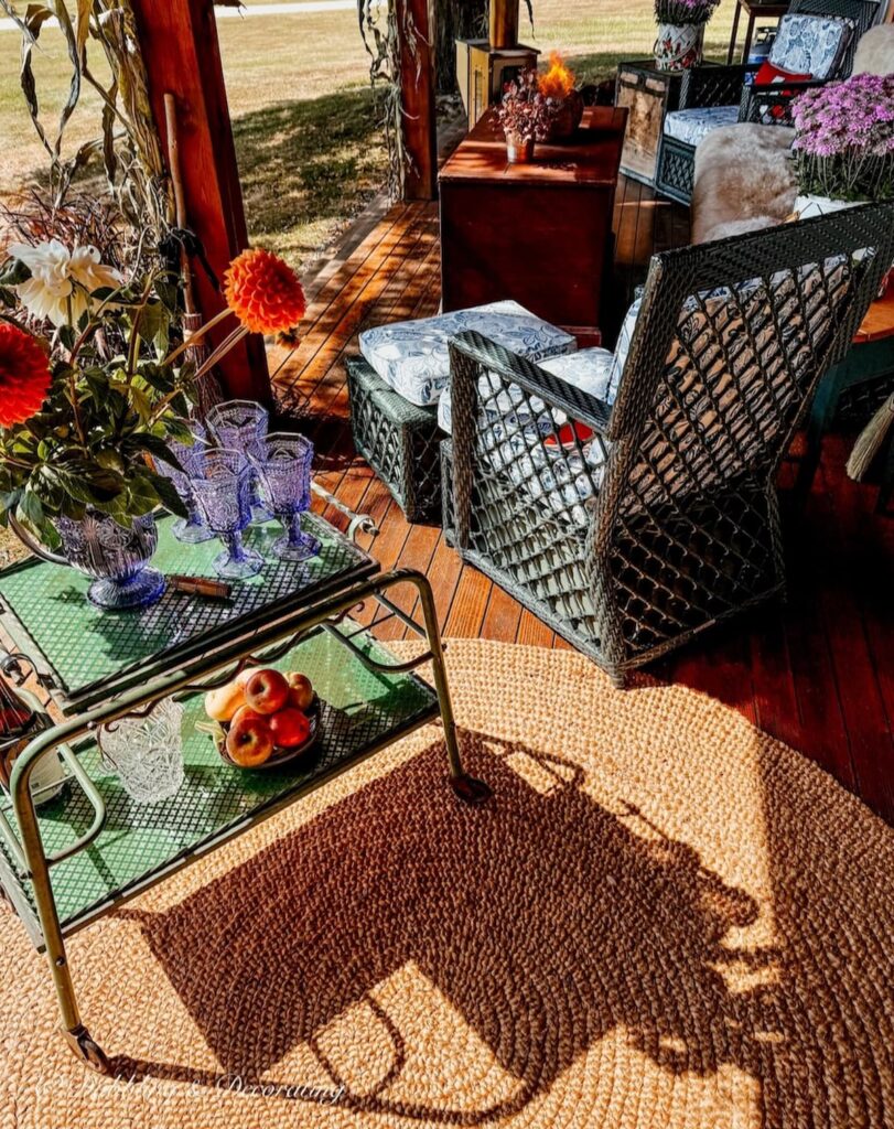 Fall porch decor ideas with antique beverage cart, natural fiber rug, and wicker seating.