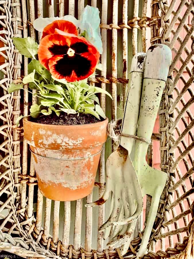Vintage terracotta pot with spring flowers and vintage garden tools in basket for vintage gifts ideas.