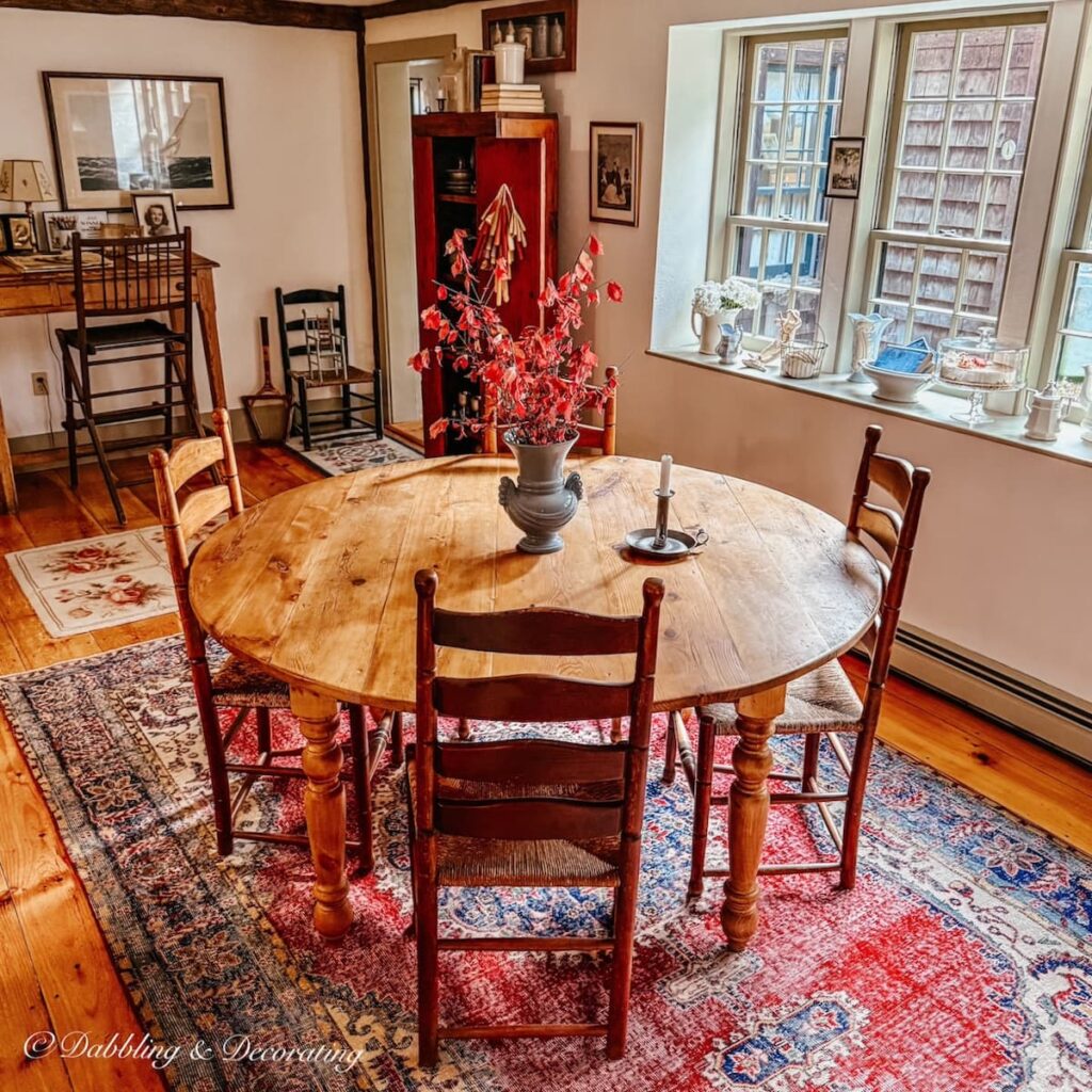 Vintage pine wood round table with four ladder back chairs and a beautiful red vintage Turkish rug in dining room in how to choose a vintage rug for wood flooring guide.
