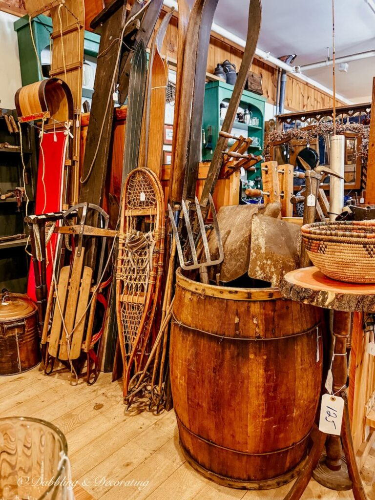 Vintage ski lodge decor displayed in an antique booth with wooden skis, sleds, toboggans, snowshoes and more at Stone House Antique Center in Chester, Vermont.