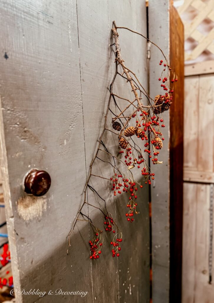 A branch of bittersweet hanging form an antique hutch door for Thanksgiving vintage decor ideas.