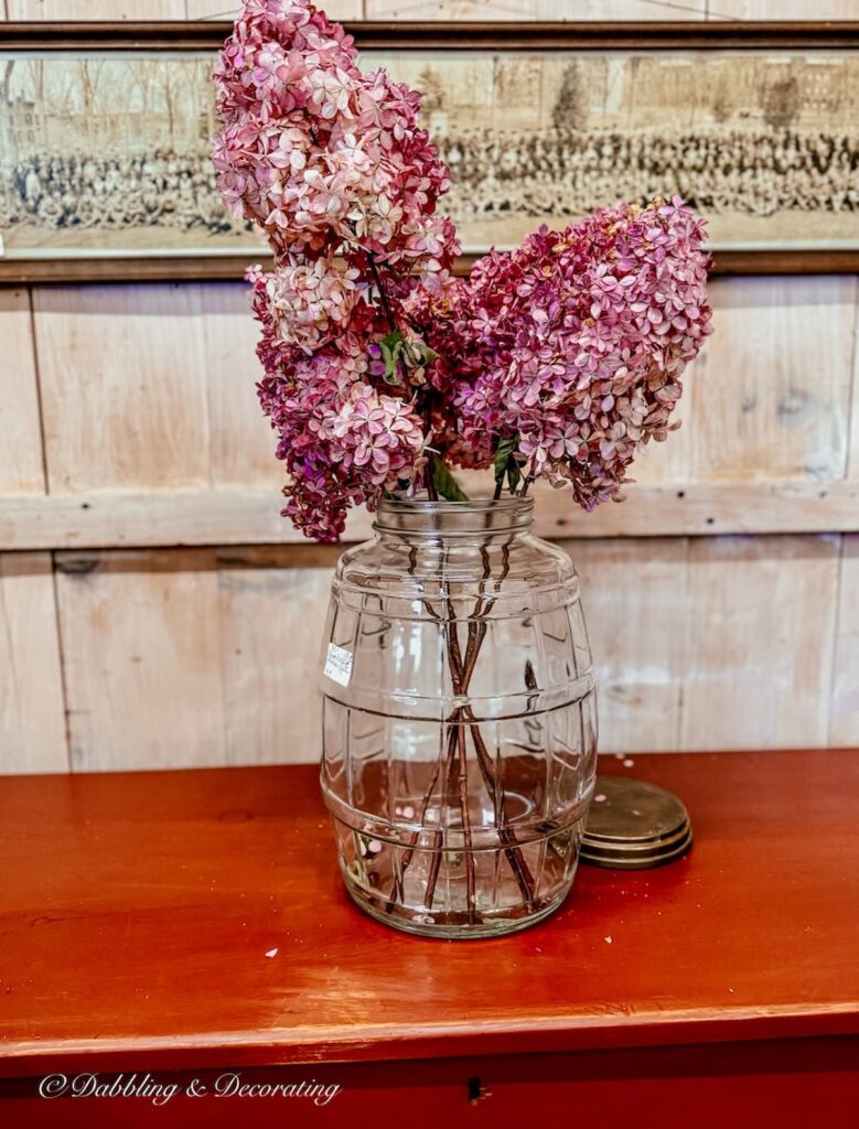 Glass jar filled with pink, mauve dried hydrangeas.