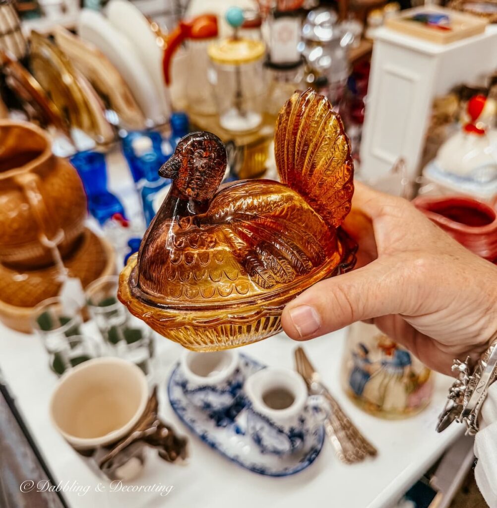 Amber glass Turkey on a nest candy dish in hand at antique store for Thanksgiving vintage decor ideas.