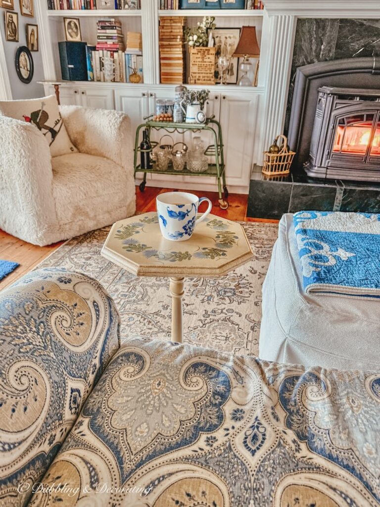 Antique side table with coffee mug in cozy living room with pellet stove fire on.