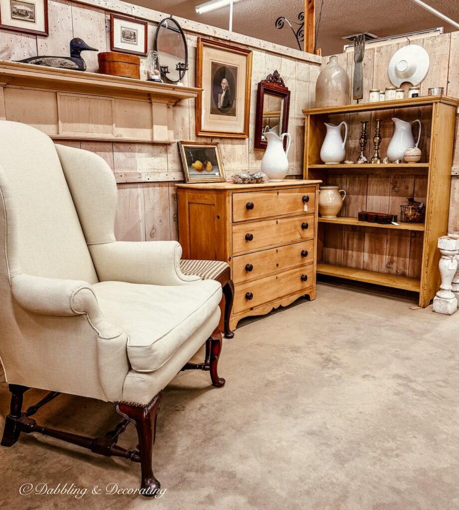 Antique booth with antique white chair and dresser cottage farmhouse style in Stone House Antique Center in Chester, Vermont.