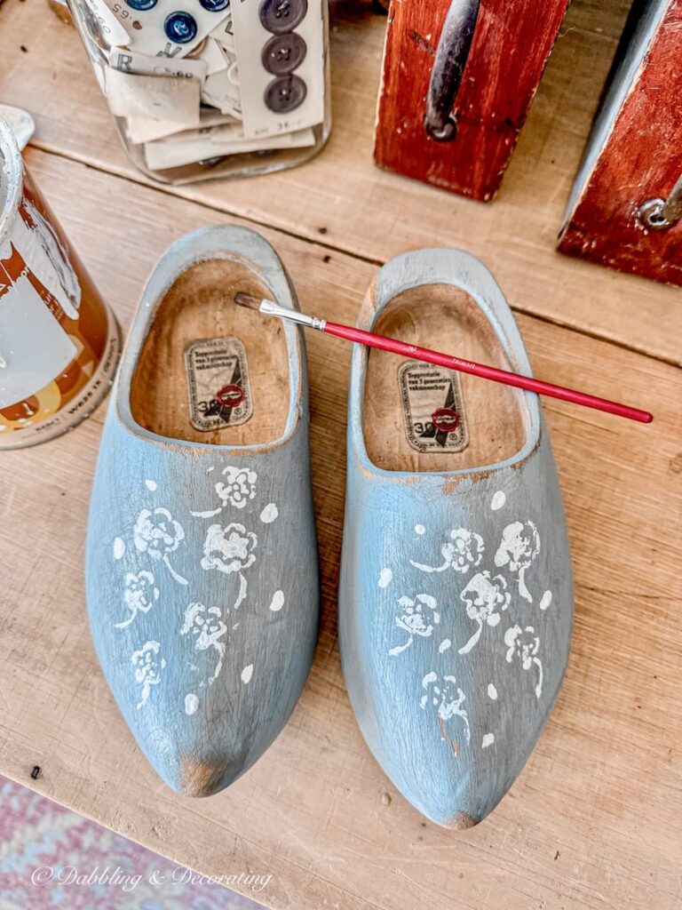 Wooden Dutch Clogs painted blue with white flowers and markings stenciled on.