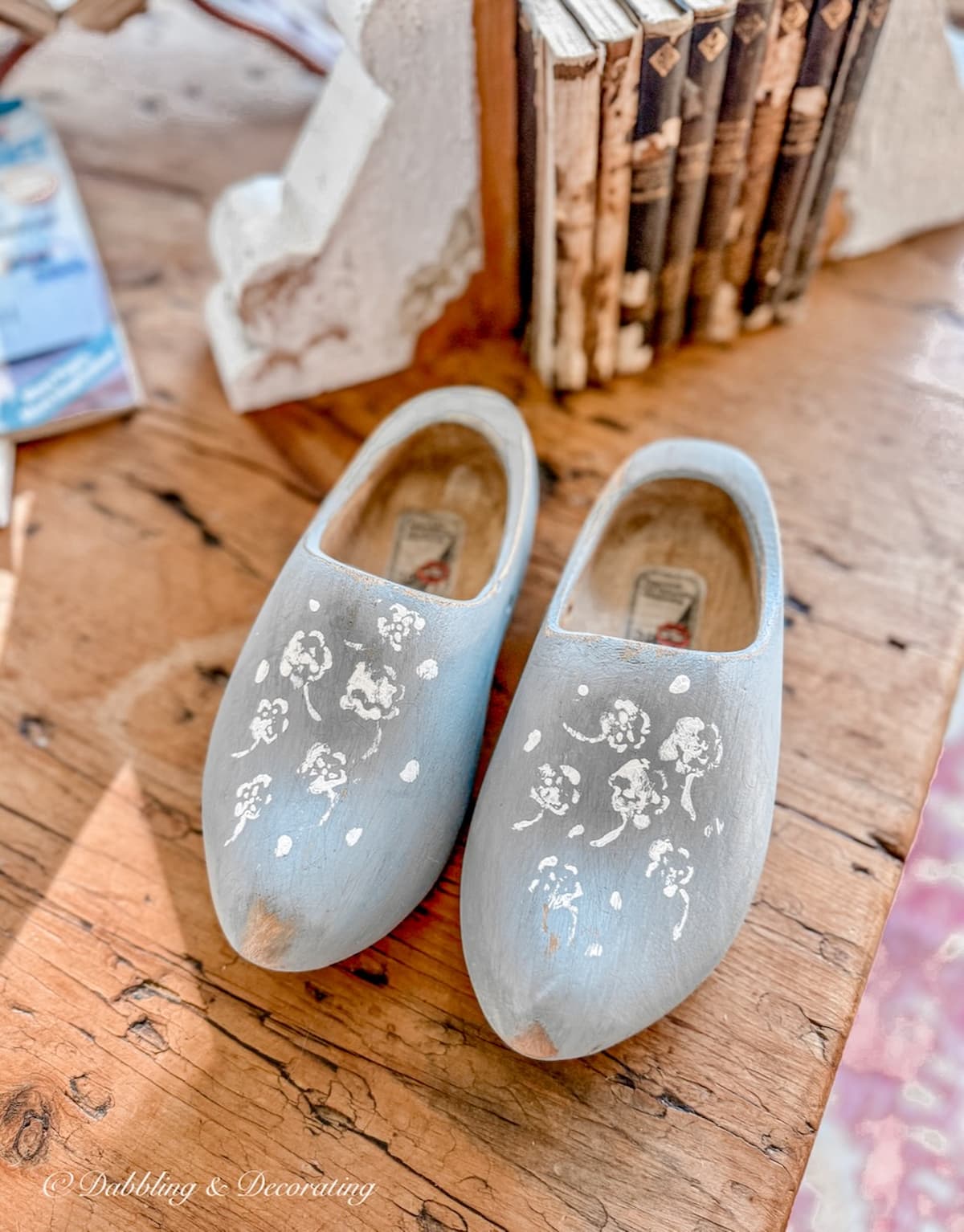 Blue Dutch Clogs with white flower stencils on coffee table.