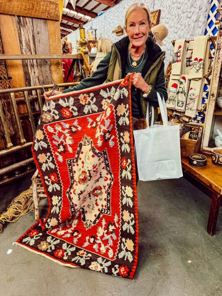 Woman holding up red nordic style vintage rug at Vintage Market Days Vermont.