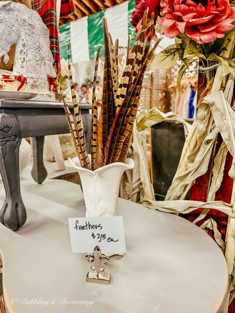 White vintage vase filled with pheasant feathers for vintage Christmas decor at Vintage Market Days Vermont.