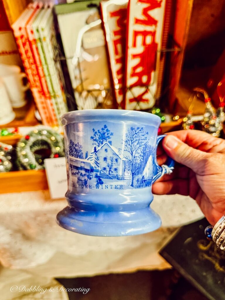 Currier and Ives blue mug with winter scene in hand at antique store.