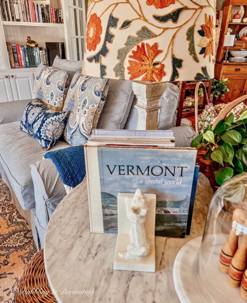 Cozy living room at Vermont home with mix and match custom slipcovered pillows and side table with Vermont book as vintage home decor gifts.