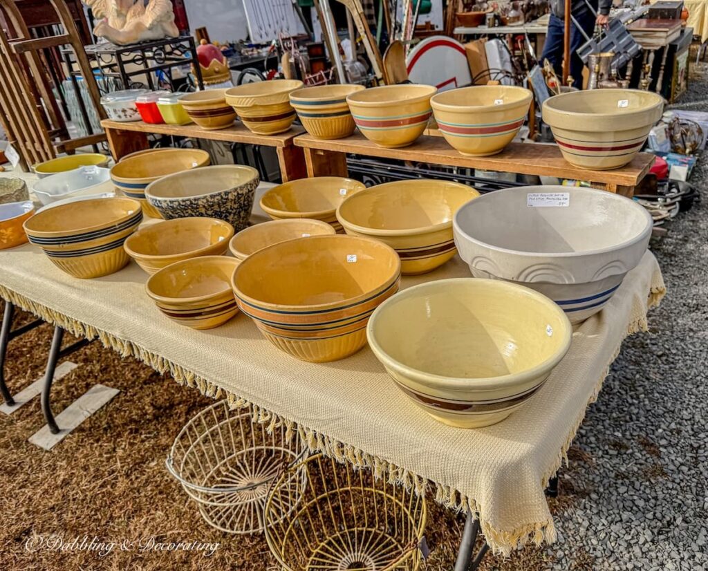 Table filled with vintage yellow ware bowls at flea market.
