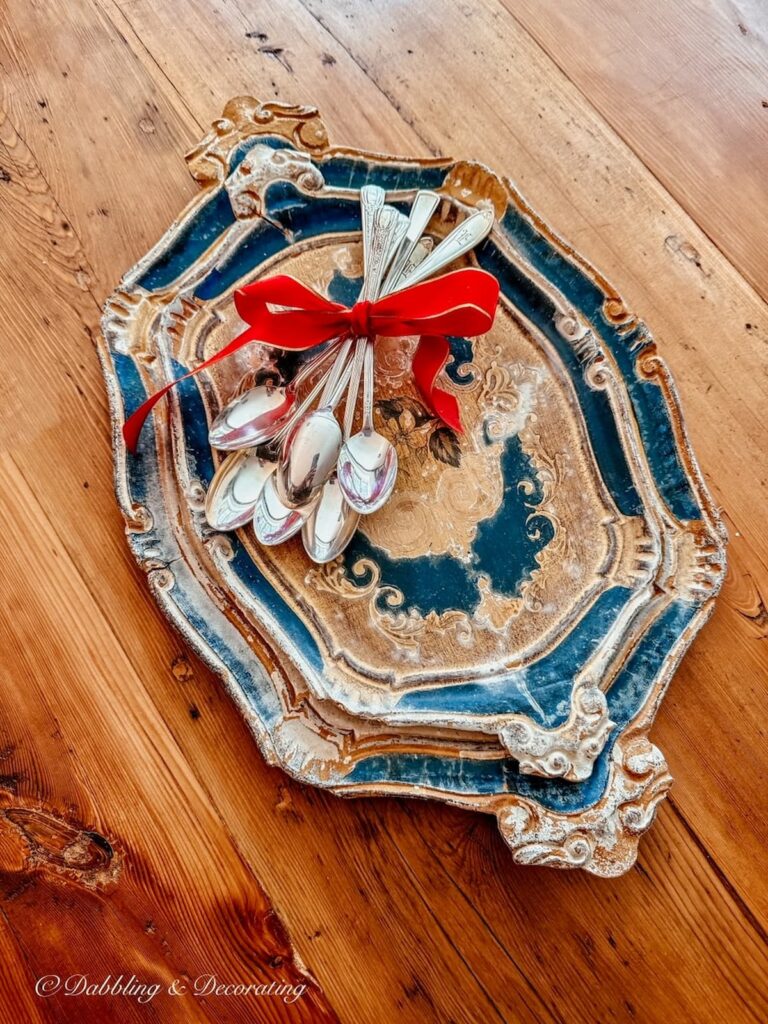 Vintage finds, Two blue and gold wooden trays with several bar silver bar spoons tied in a red bow.