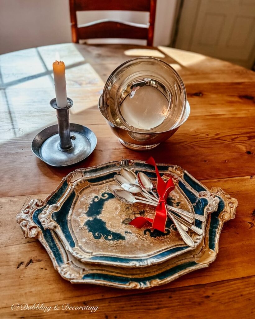 Vintage finds, Two blue and gold wooden trays with several bar silver bar spoons tied in a red bow and two silver bowls.