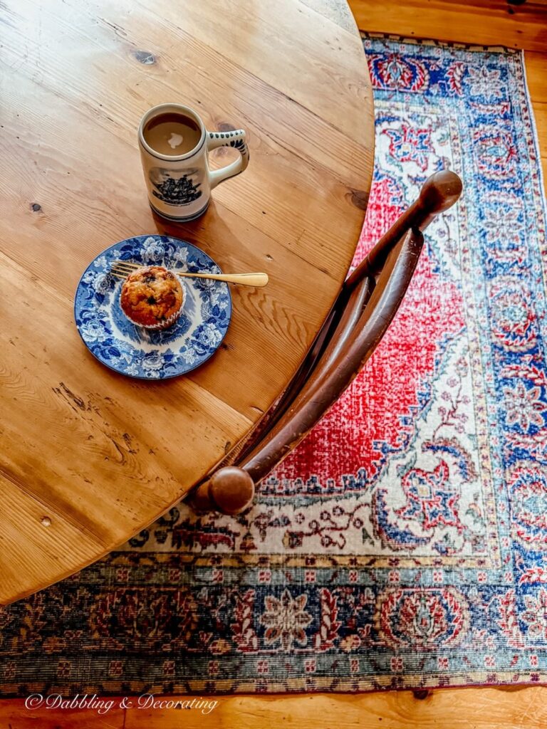 How to choose a vintage rug in a dining room with a round table and ladder back chairs on a vintage red rug.
