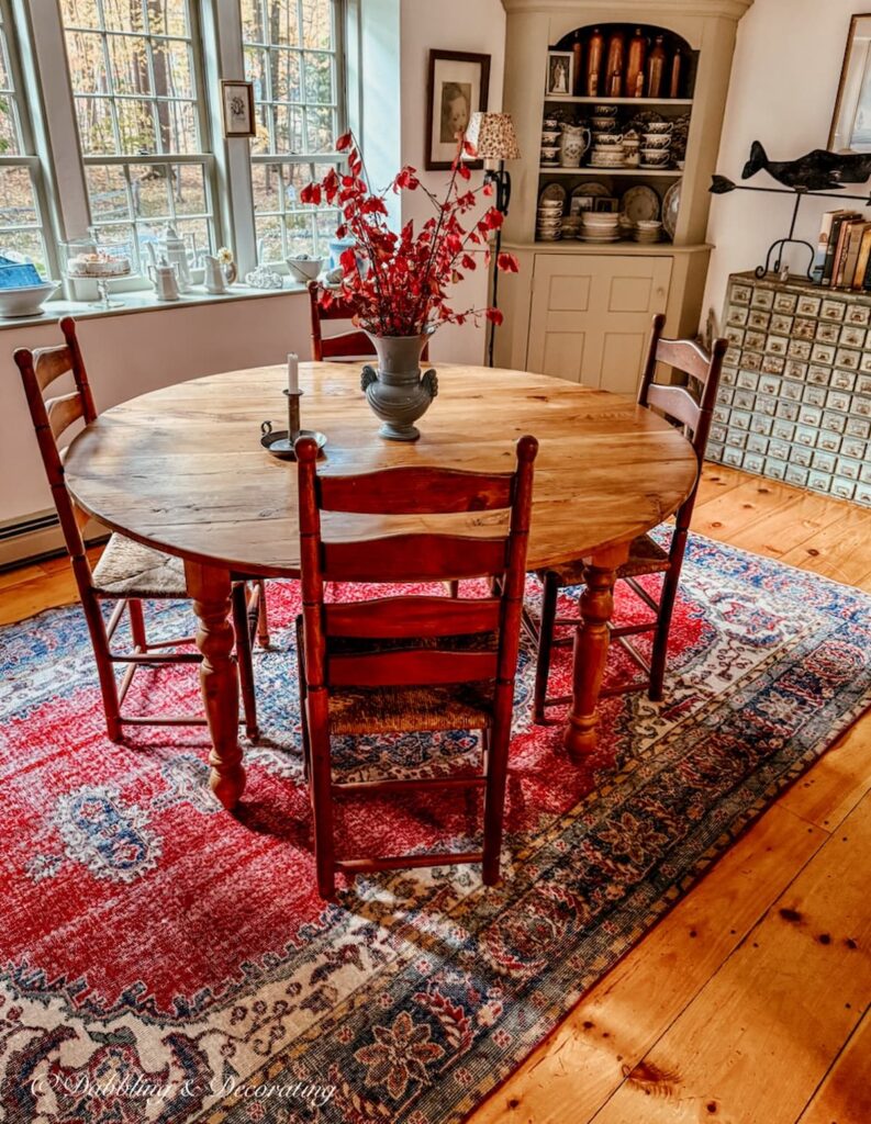 How to choose a vintage rug with a red rug in a dining room with pine wood flooring and a round table and chairs.