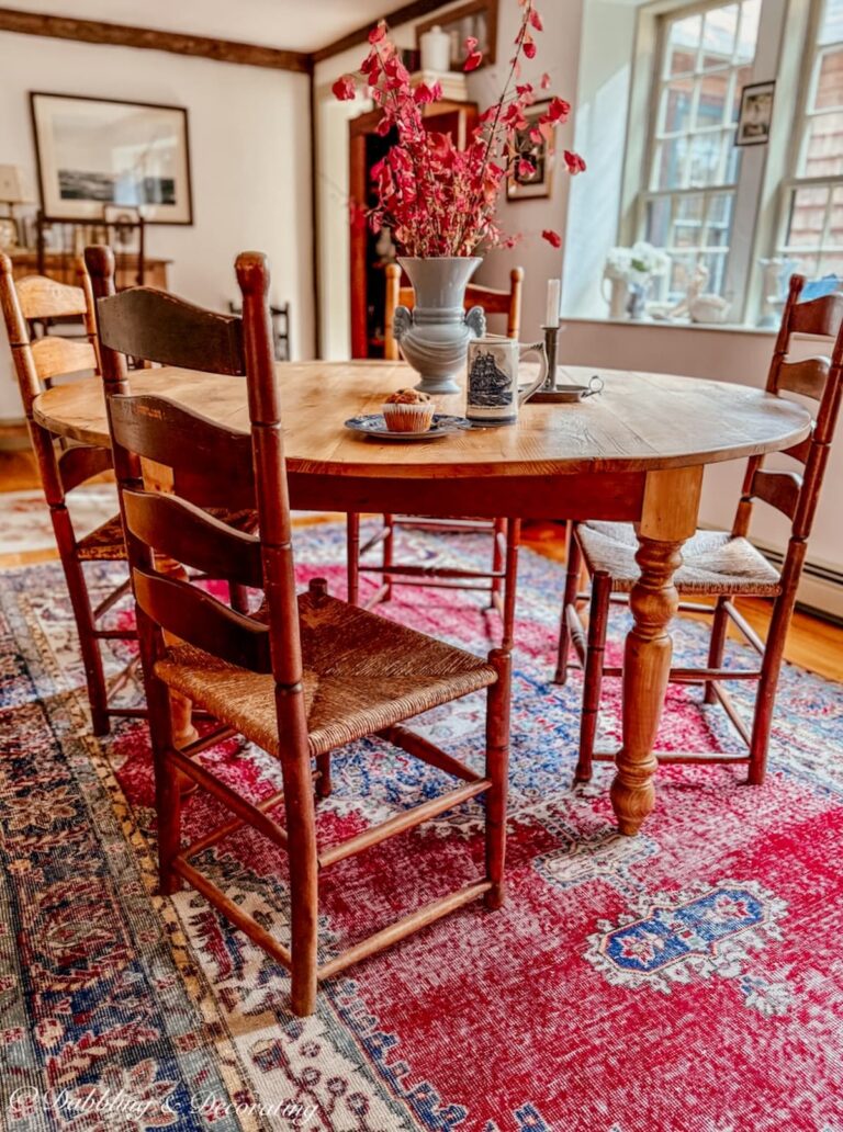 How to choose a vintage rug for a dining room with a round table and ladder back chairs in red with pine wood floors.