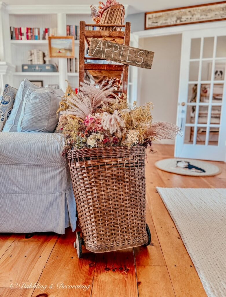 Vintage French basket filled with dried pink fall florals and pink hydrangeas in a vintage styled living room.