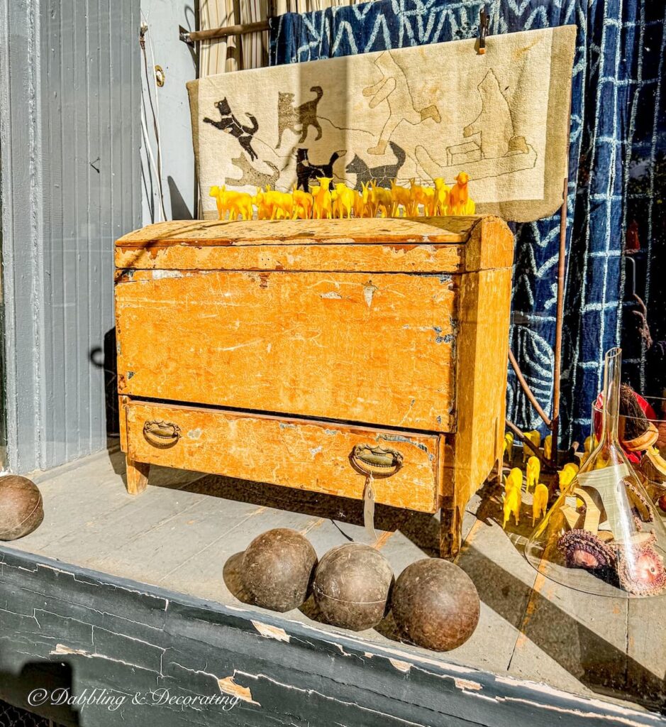 Window shopping on Warren Street's mile long antiquing, yellow antique dresser and antique bowling bowls in window.