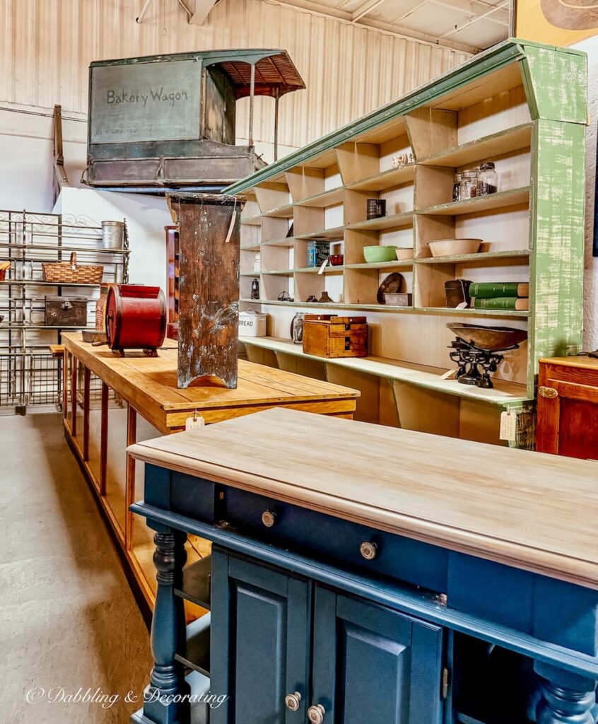 Antique booth inside The Antique Warehouse Hudson NY with large kitchen islands, cabinets, and a large Bakery Wagon.