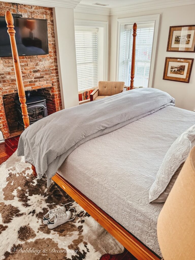 Mercer bedroom with four poster bed, cowhide rug and fireplace at the WM Farmer and Son Inn in Hudson, NY.
