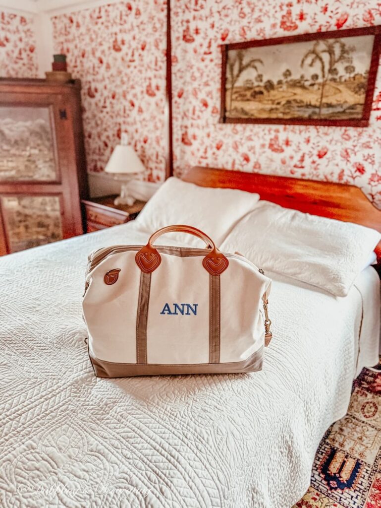 Monogrammed duffel bag on canopy bed at Clark Currier Inn in Newburyport MA before visiting Todd Farm Flea Market