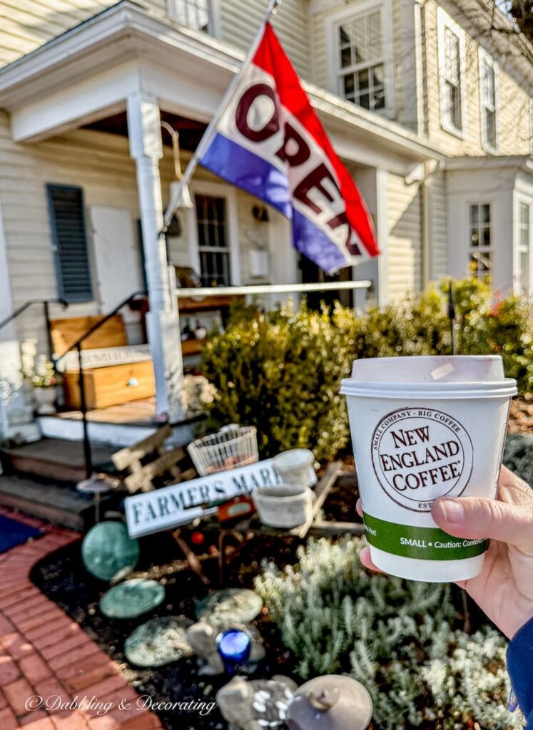 The Vintage Peddler Open flag and New England coffee mug in hand at Todd Farm Antiques and Flea Market Shops.