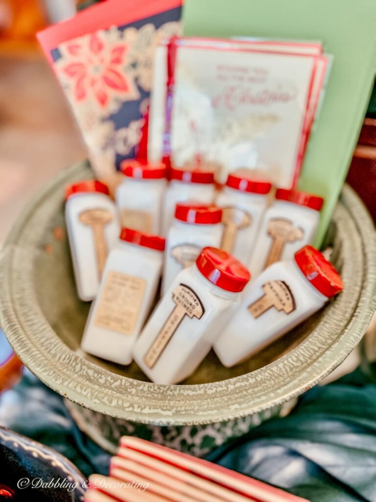 Set of vintage milk glass spice jars with red tops and labels in bowl.
