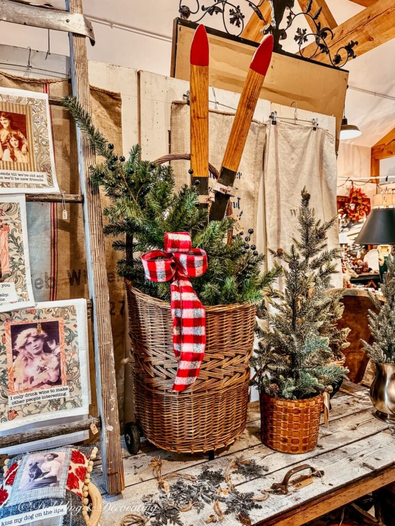 Antique French basket with evergreens, red plaid bow and wood skis displayed inside The Barn at Todd Farm in Rowley, Massachusetts.