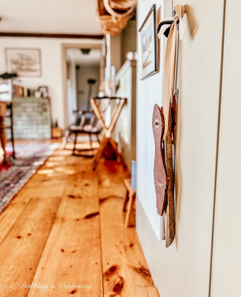 Antique racing ice skates with ribbon hanging from a latched door in coastal Maine home.