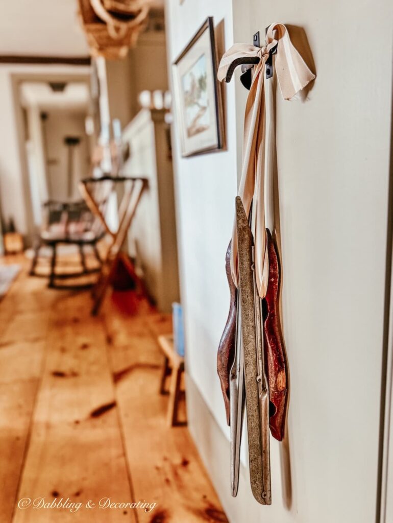 Antique racing ice skates with ribbon hanging from a latched door in coastal Maine home.