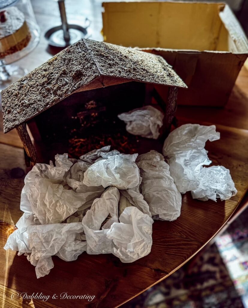 Vintage Christmas manger with wrapped figurines on the dining room table.