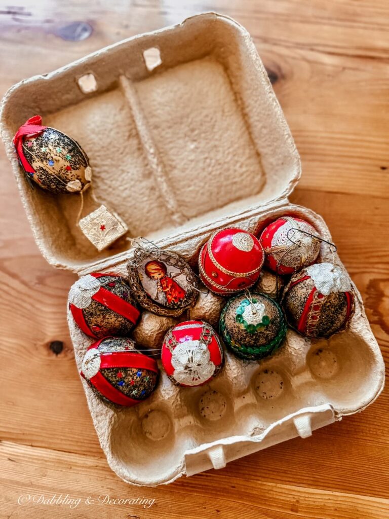 Vintage Christmas decorations: handmade egg shell Christmas ornaments in egg carton in various christmas colors.