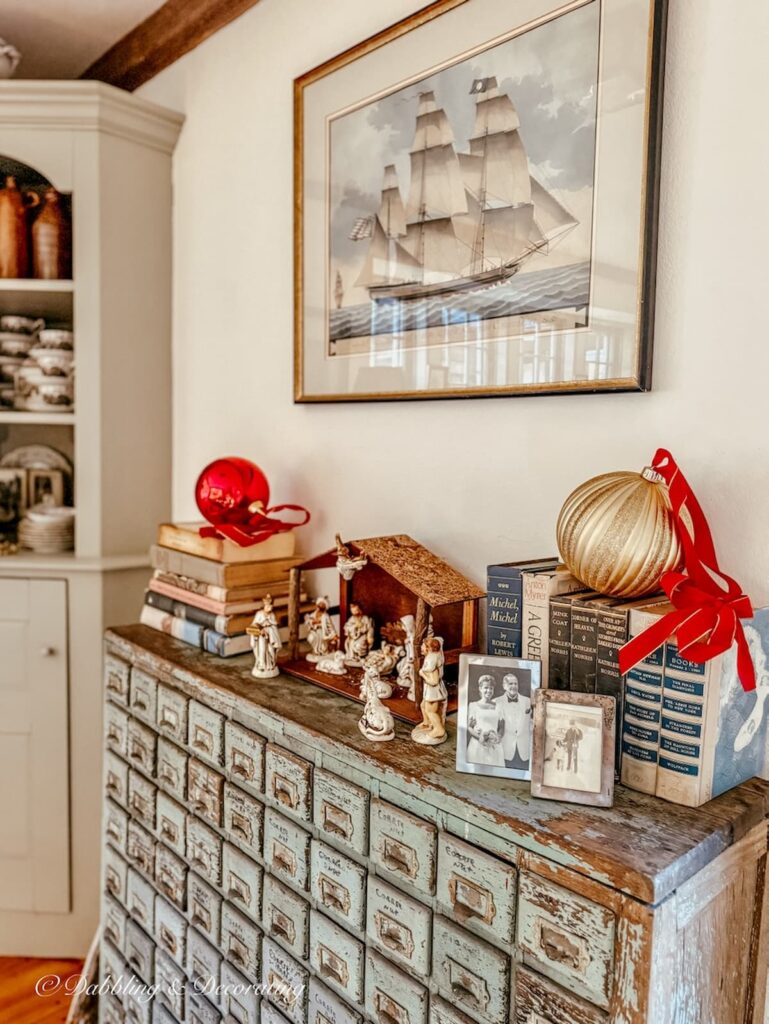 Antique apothecary with vintage Christmas decorations, Christmas manger, vintage books, and large Christmas ornaments.