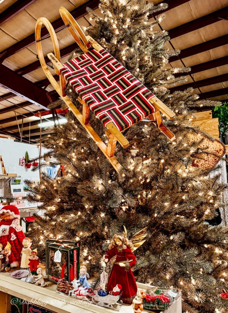 Cool vintage wooden sled with red red webbing hanging on Christmas tree at Barge Canal Market antiquing in Burlington, Vermont.