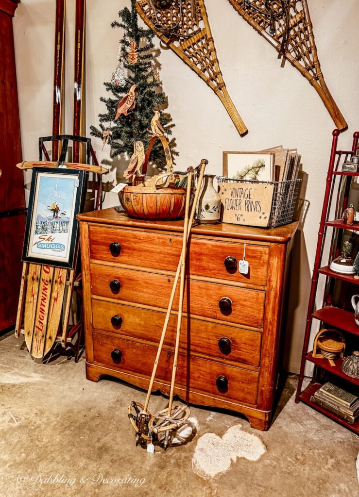 Antique wooden dresser with large vintage wooden ski poles and snowshoes on wall in vendor booth antiquing in Burlington, Vermont.