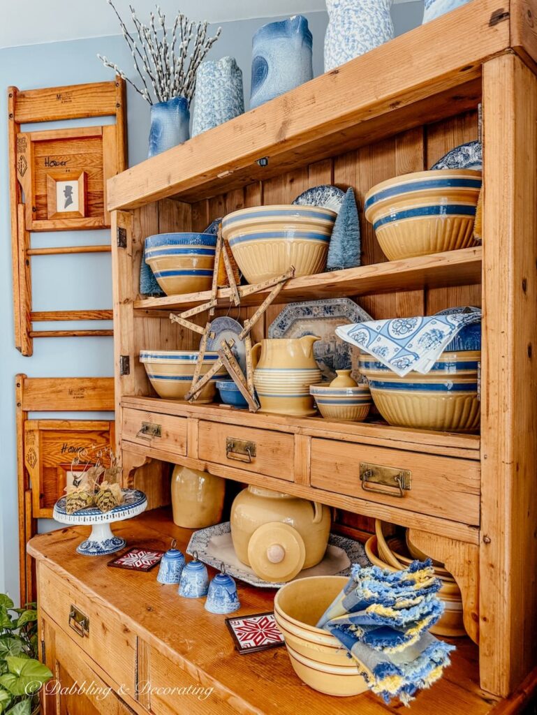 Vintage pine hutch with yellow ware collection and a vintage folding ruler star with blue accents.