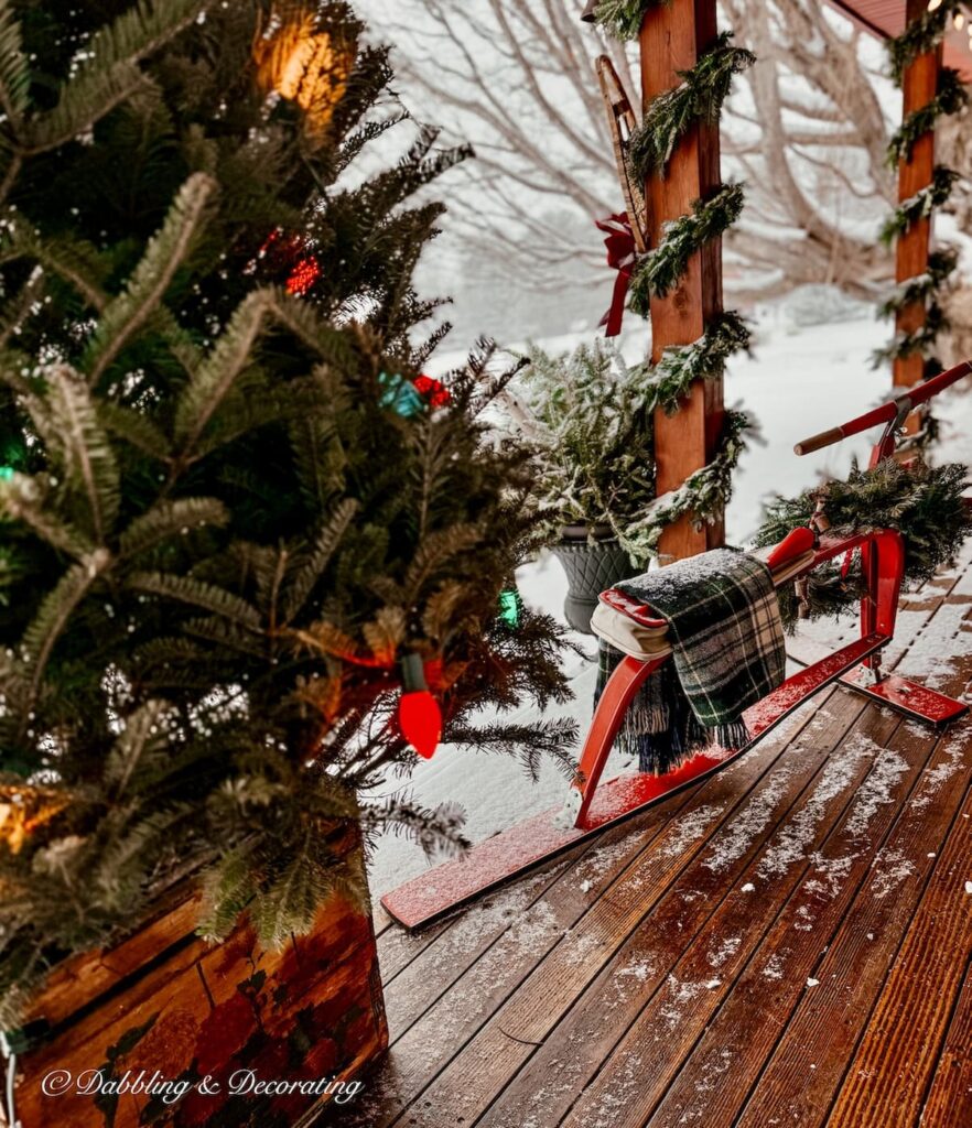 Outdoor Christmas tree in an old crate with Retro colored lights and a French Alps vintage ski bob inn Vermont home's Après Ski Christmas Porch Decor