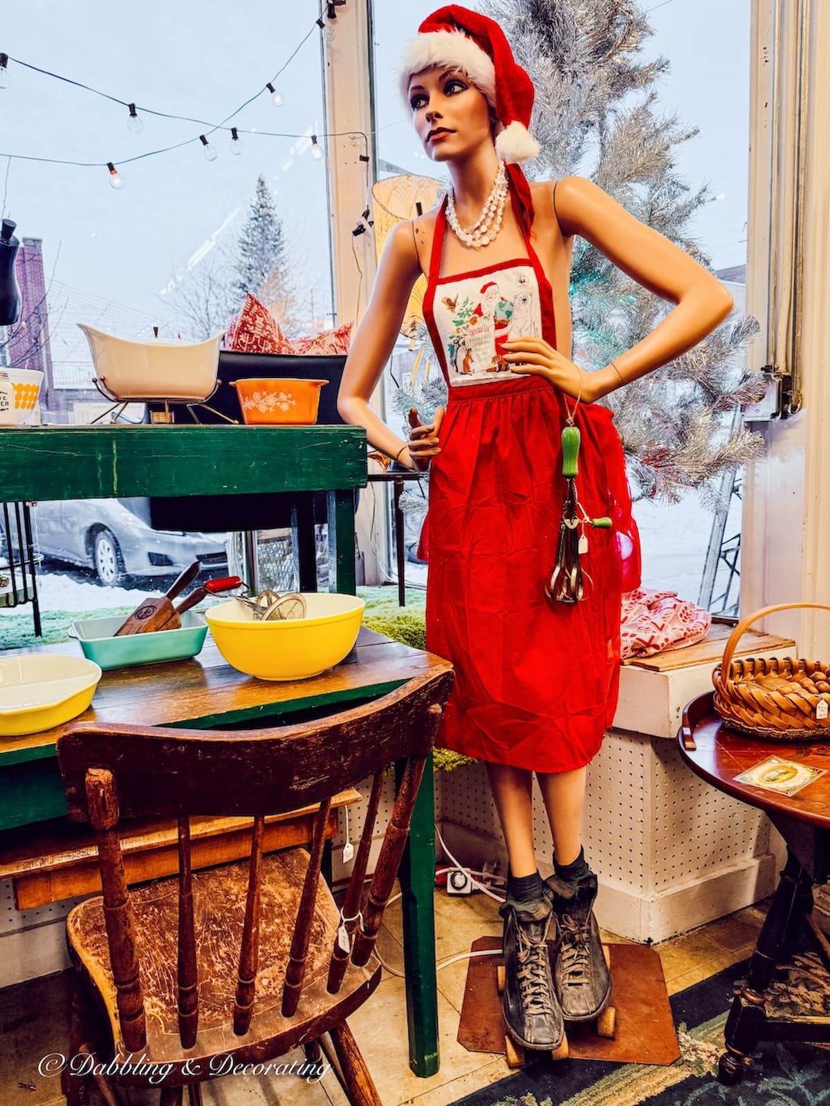 Life like female mannequin with a red apron, antique roller skates and kitchen utensil inside Across the Street Antique shop in Brandon, Vermont.