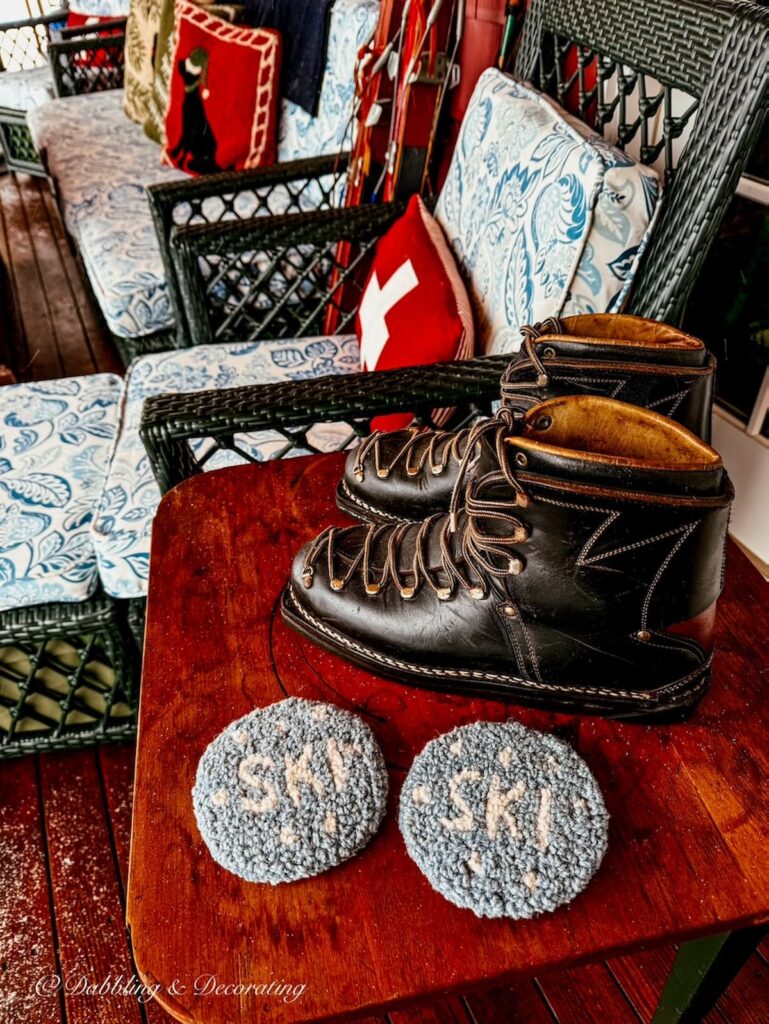 Vintage leather black ski boots on apres ski Christmas porch decor with two Chandler 4 Corners SKI coasters found at antique shops in Brandon, Vermont.