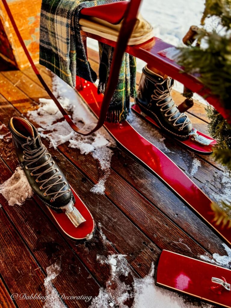 Vintage black ski boots on French ski bob foot skis in apres ski Christmas porch decor.