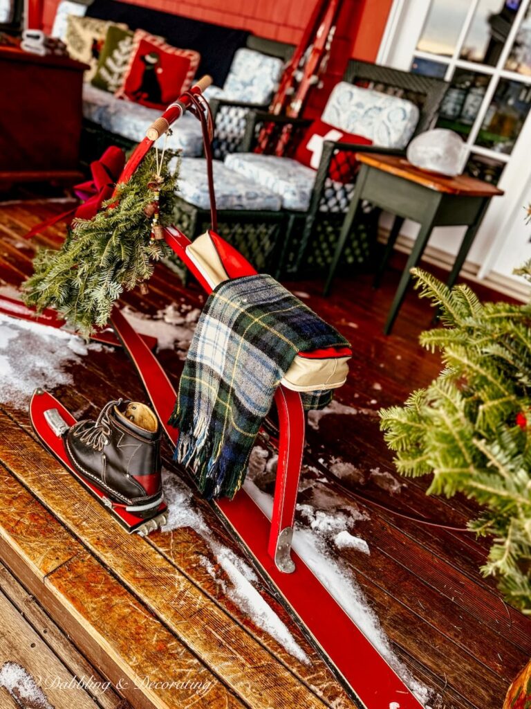 Vintage French Ski Bob in Après Ski Christmas Porch Decor with vintage black ski boots, and plaid blanket.