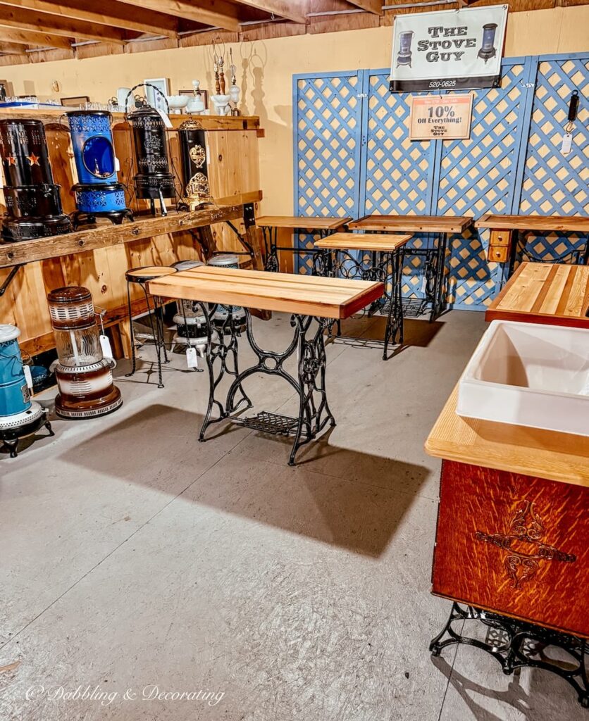 Vendor booth at The Willows flea market in Maine filled with vintage sewing machine tables and antique stoves.