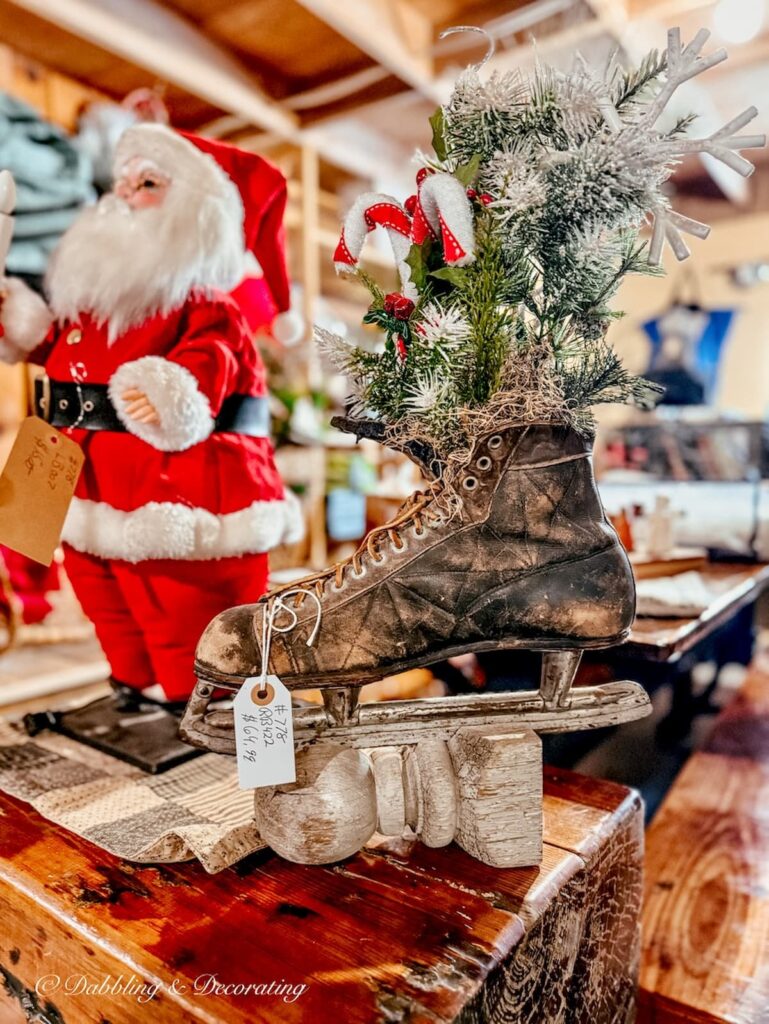 Antique black men's ice skate on architectural salvage piece with evergreens in Santa at The Willows flea market in Maine.