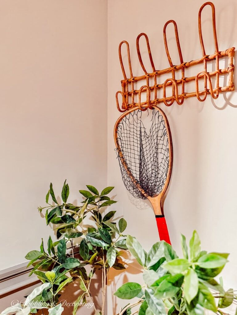 A wooden coat rack with a fishing net hanging in the lodge decor at The Wolf Cove Inn at Tripp Lake in Poland, Maine.