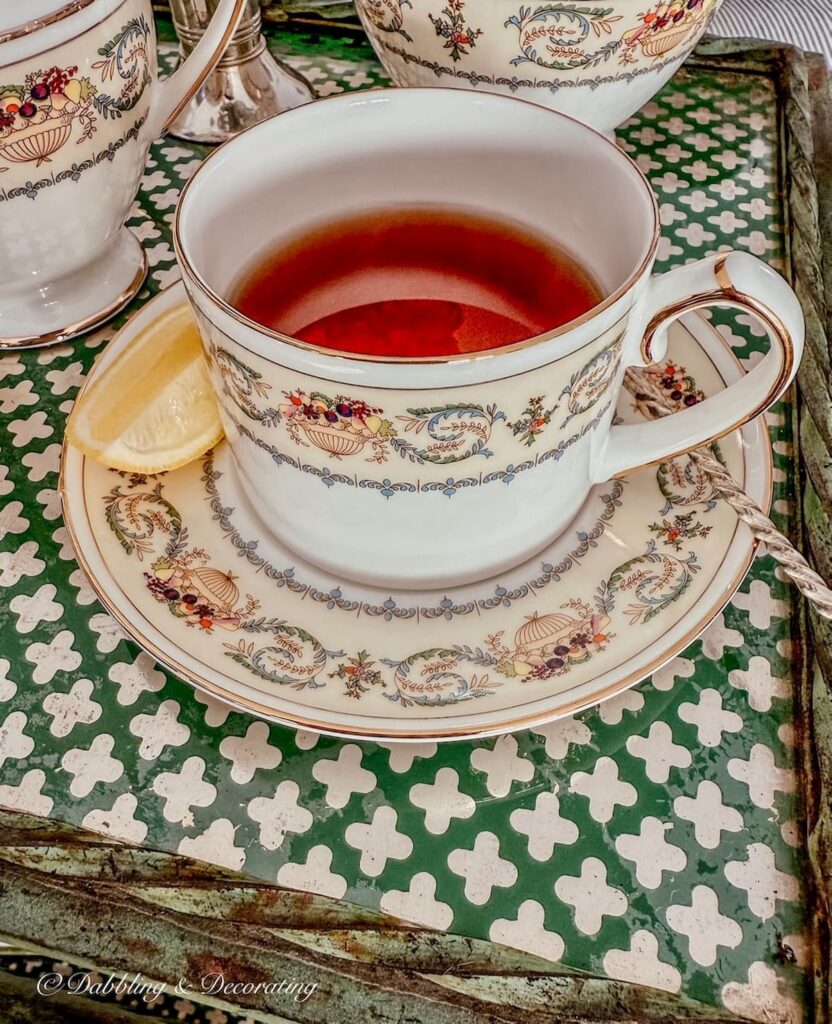 Aynsley Banquet tea cup and saucer with silver spoon on antique tea cart.