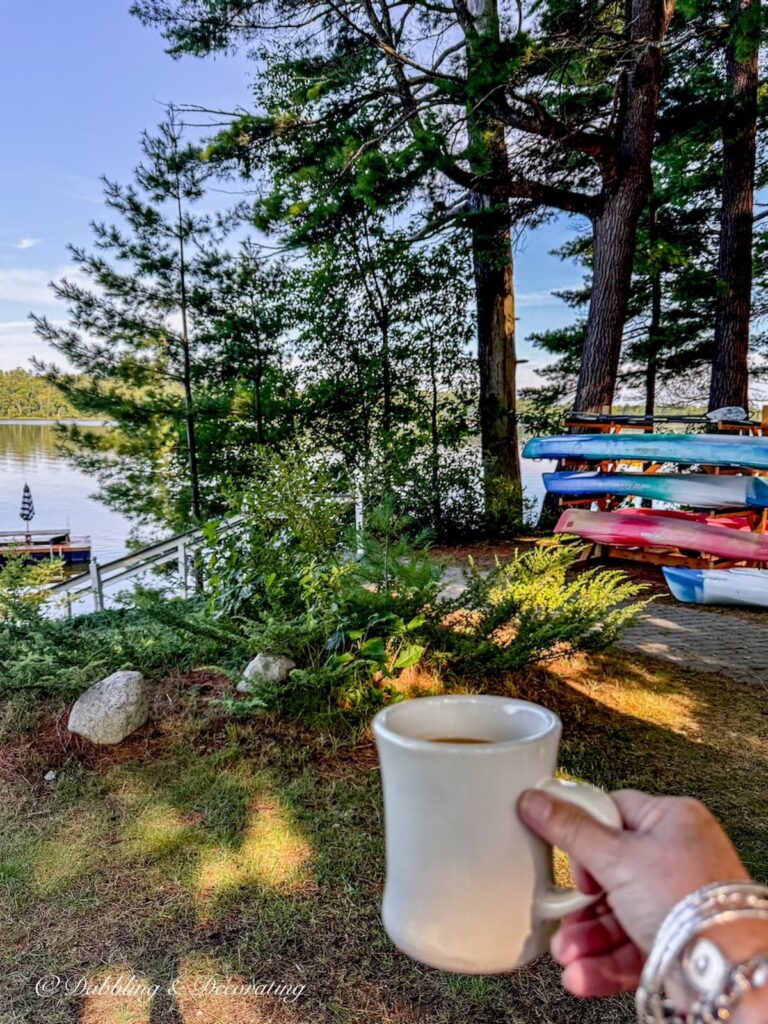Coffee mug in hand on an early morning at Wolf Cove Inn in Poland, Maine with Lake Tripp and Kayaks in the background.