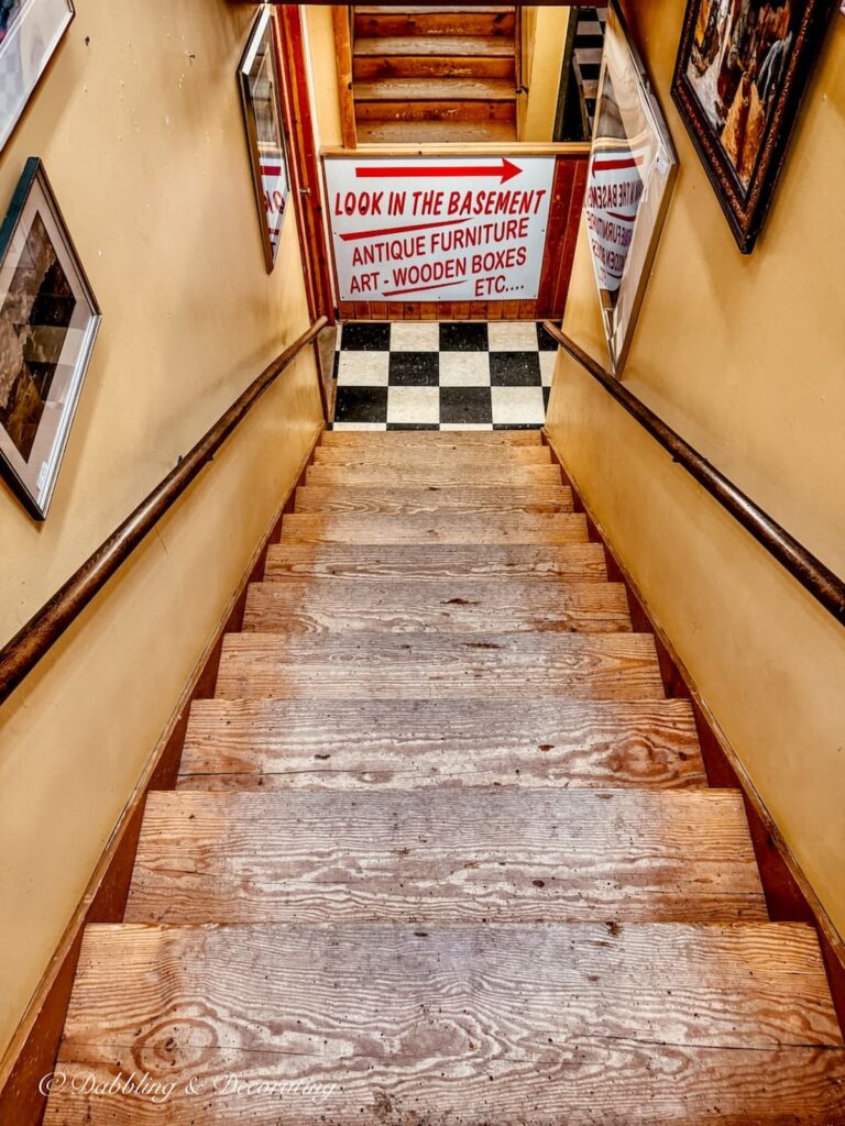 Stairs going down to the basement floor with sign at The Vermont Antique Mall