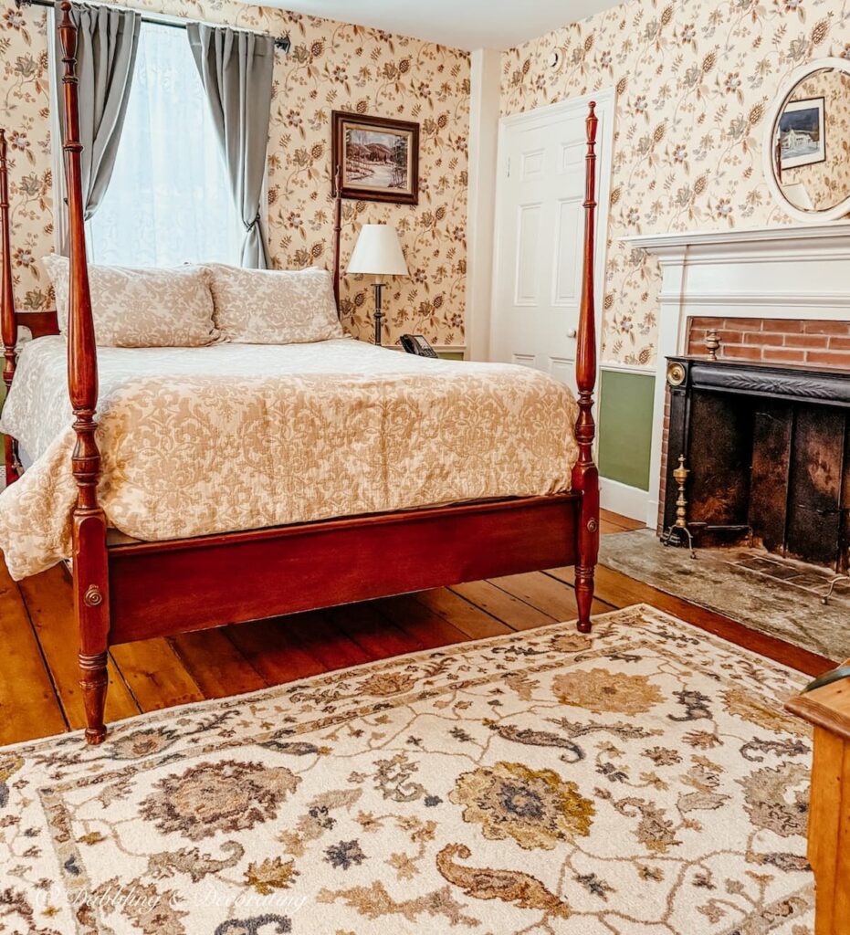 Room 5 inside the Quechee Inn at Marshland Farm in Vermont with four poster antique bed, wallpaper and antique fireplace.
